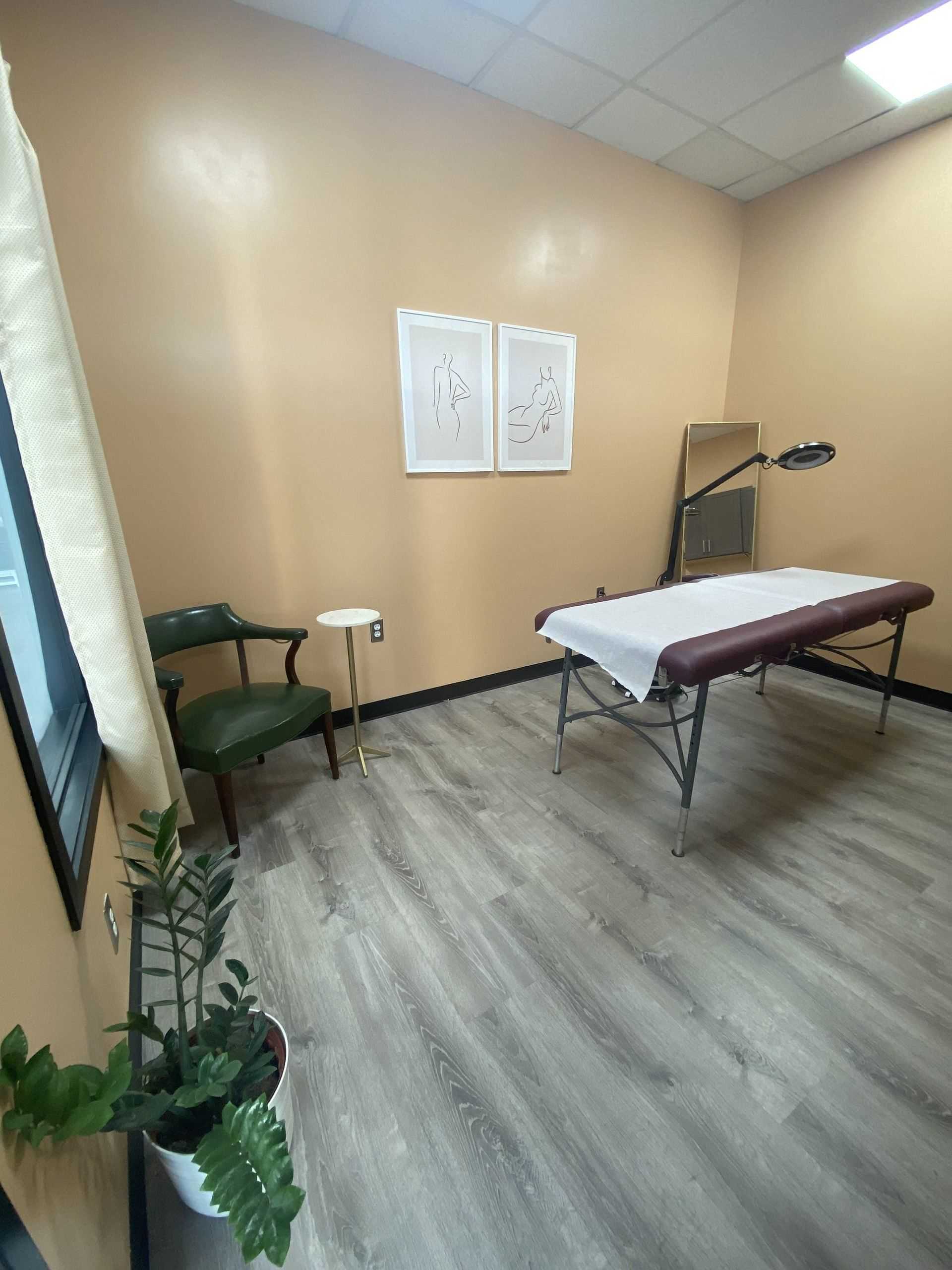Massage therapy room with a massage table, chair, and minimalist wall art.